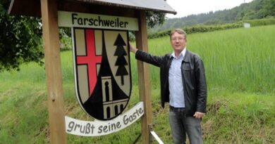 Historiador Toni Jochem diante da placa indicativa da cidade de Farschweiler, na região do Hunsrück, no Estado da Renânia-Palatinado, na Alemanha.